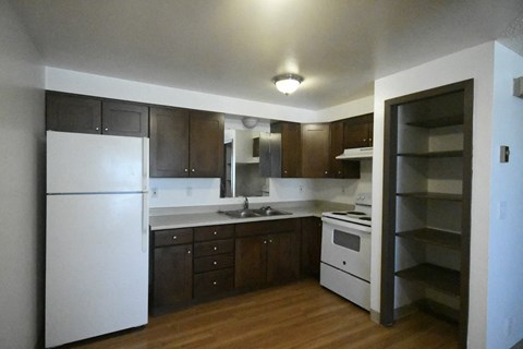 an empty kitchen with white appliances and wooden cabinets