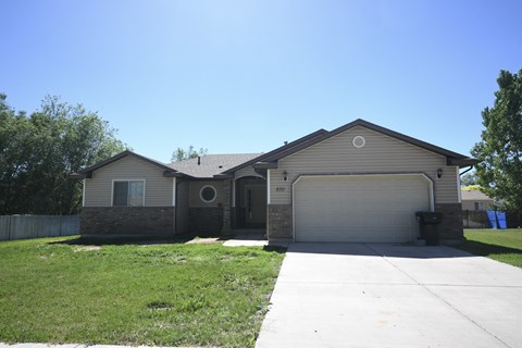 a beige house with a garage door and a lawn
