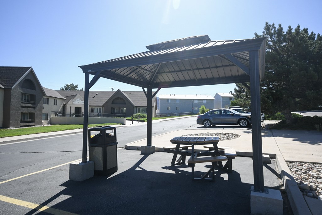 a picnic table and a trash can in a parking lot
