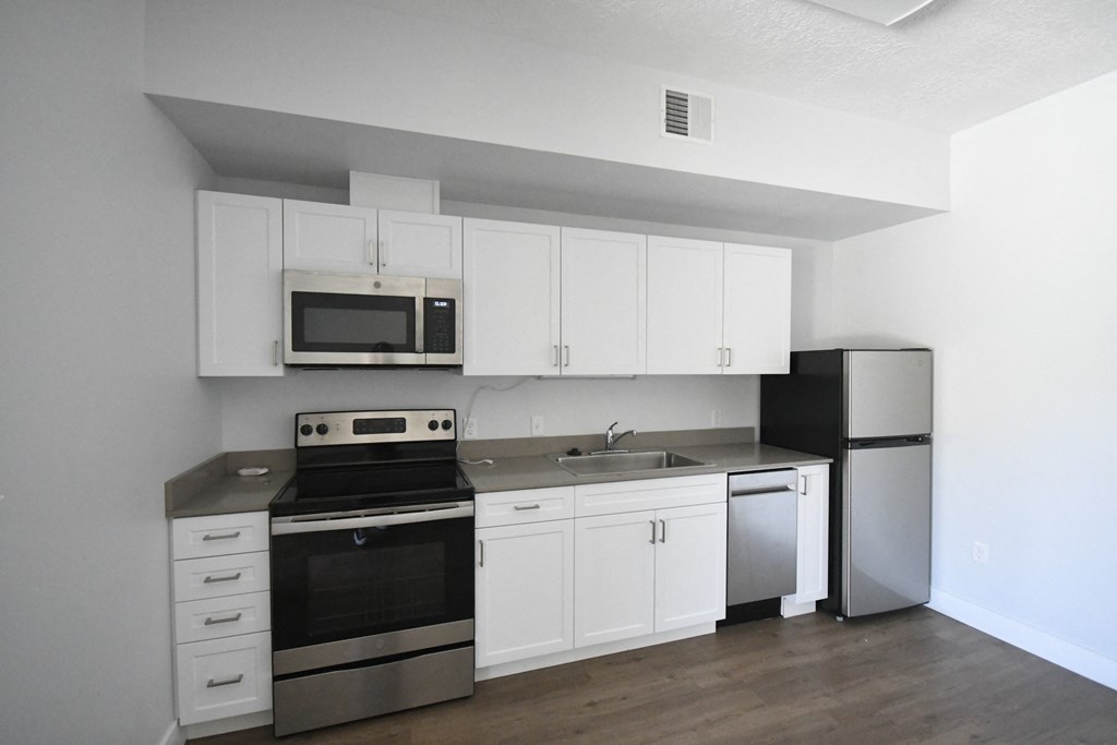 an empty kitchen with white cabinets and stainless steel appliances