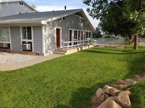 a gray house with a porch and a grass yard
