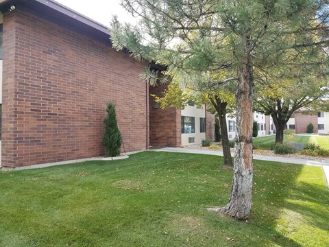 the outside of a brick building with grass and trees