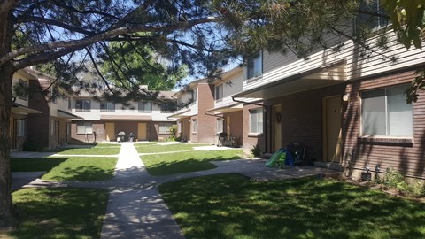 a walkway between two apartment buildings with grass and trees