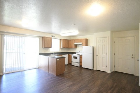 an empty kitchen with wood flooring and white appliances