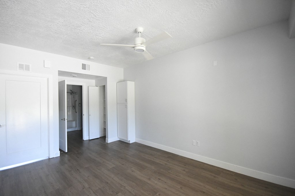 an empty living room with white walls and a ceiling fan