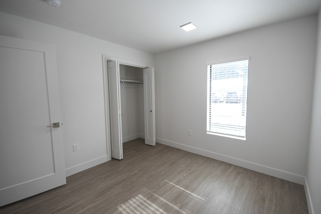 a bedroom with white walls and a window and a door