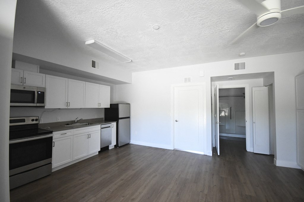 an empty kitchen with white cabinets and stainless steel appliances