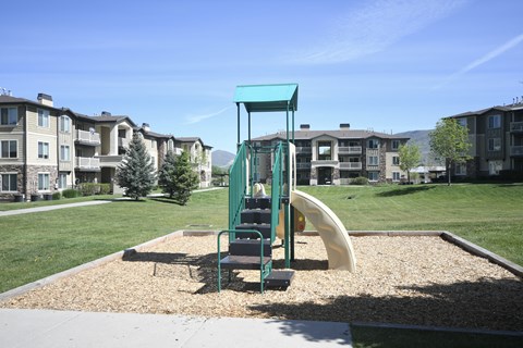 a playground with a slide in front of an apartment complex