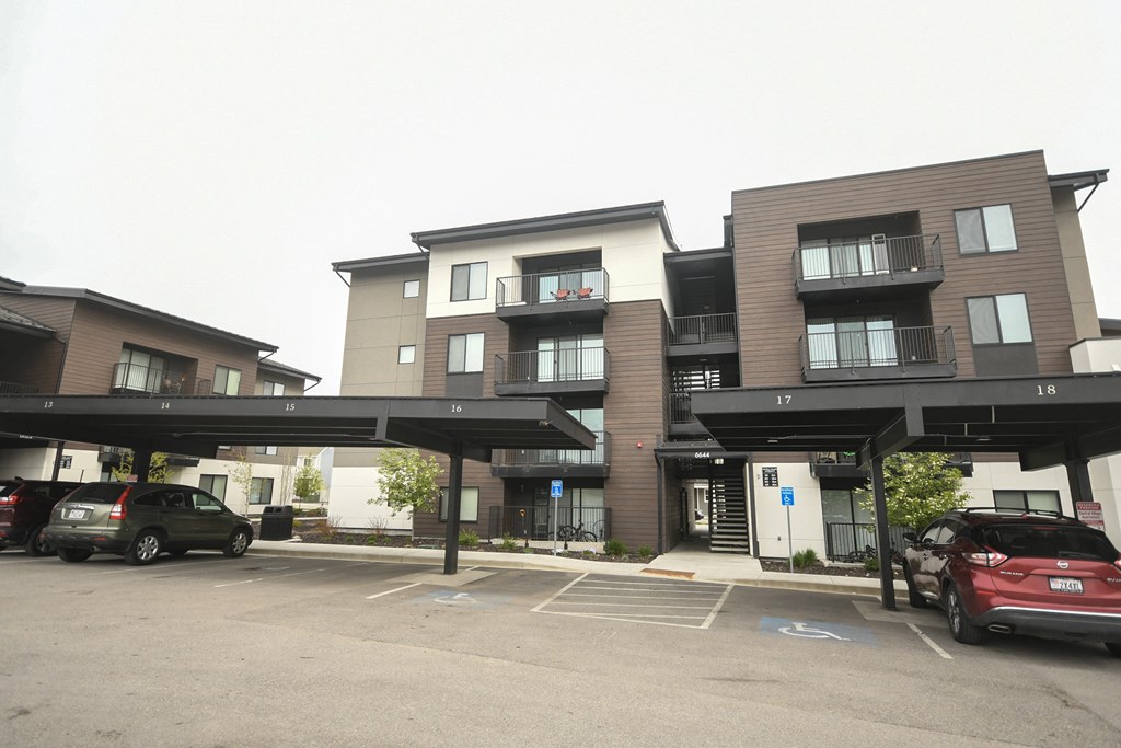 a parking lot with cars parked in front of apartment buildings