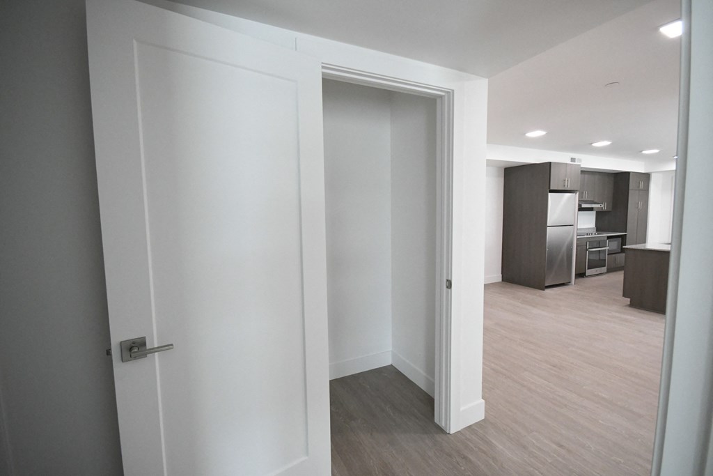 an open doorway into a living room with a kitchen in the background