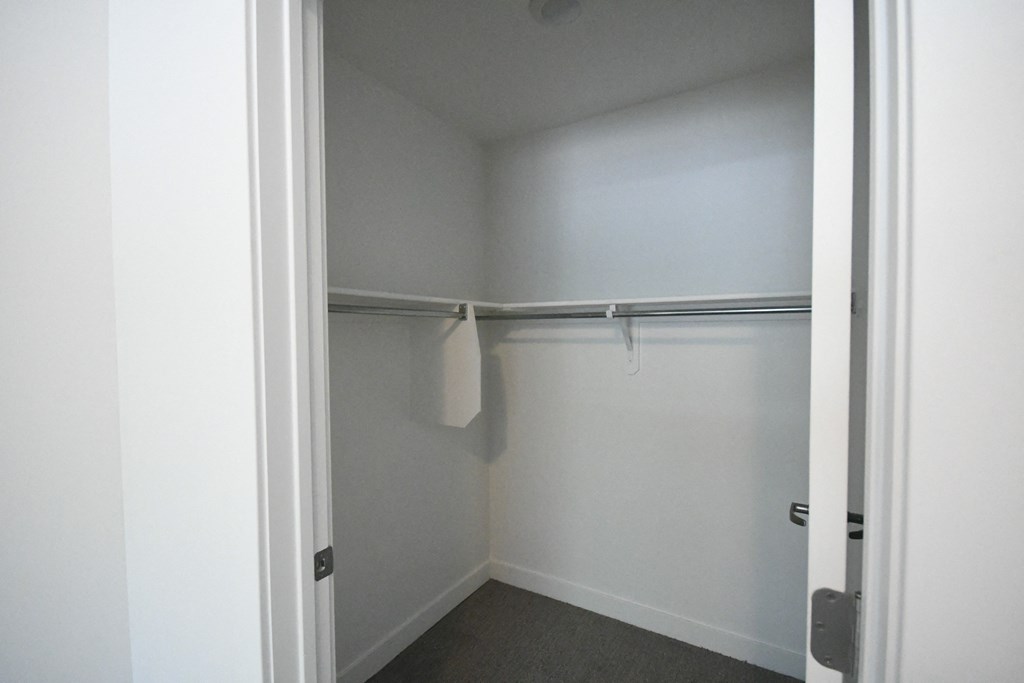 an empty closet in a white room with a towel rack