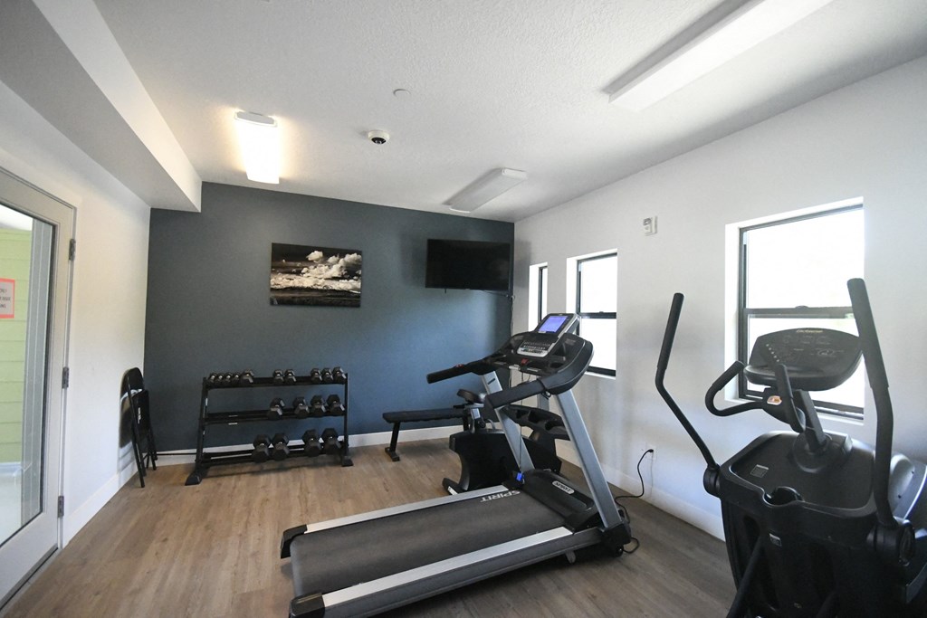 a gym with exercise equipment and a wall mounted tv