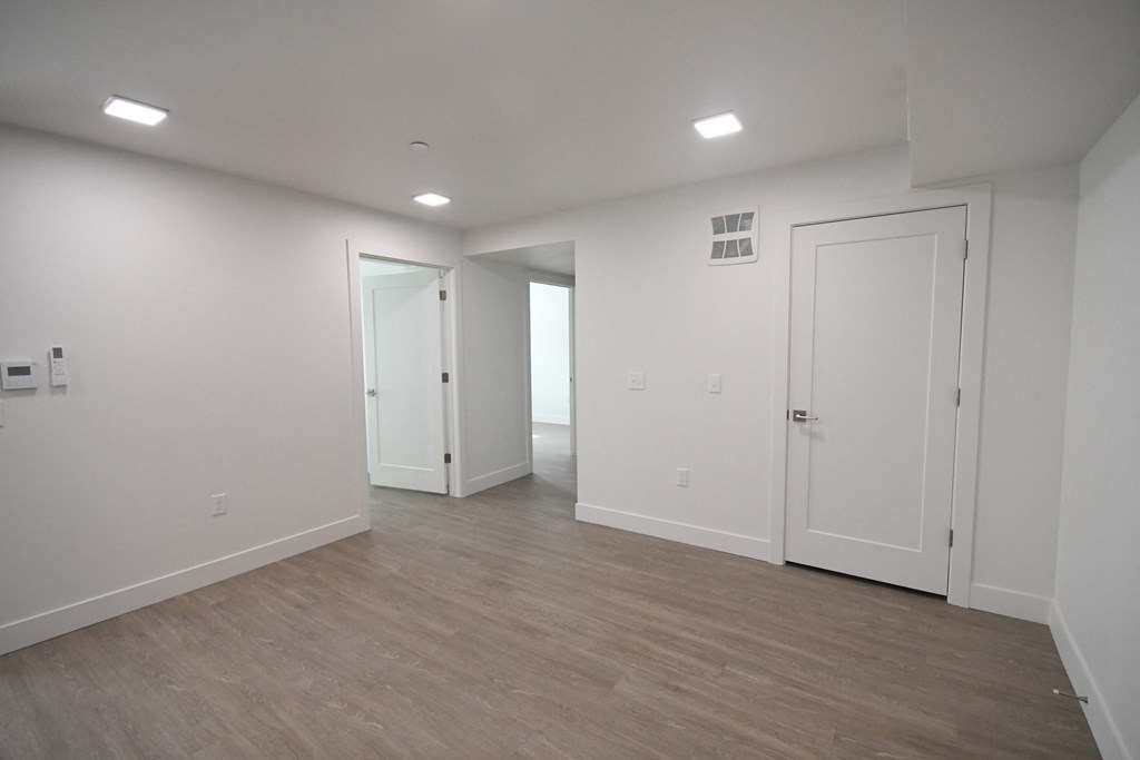an empty living room with white walls and a wooden floor