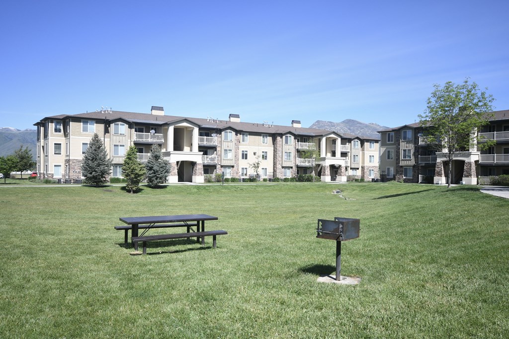 a park with a picnic table in front of an apartment building