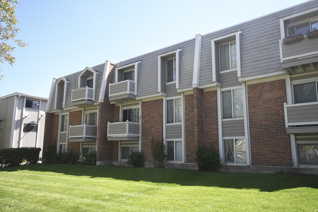 an apartment building with a green lawn in front of it