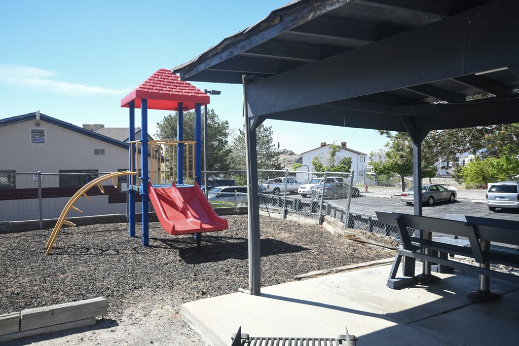 a playground with a red swing set in a park