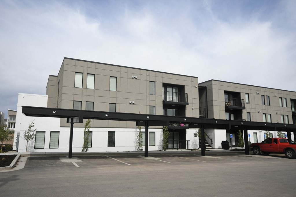 an apartment building with a parking lot and a red car