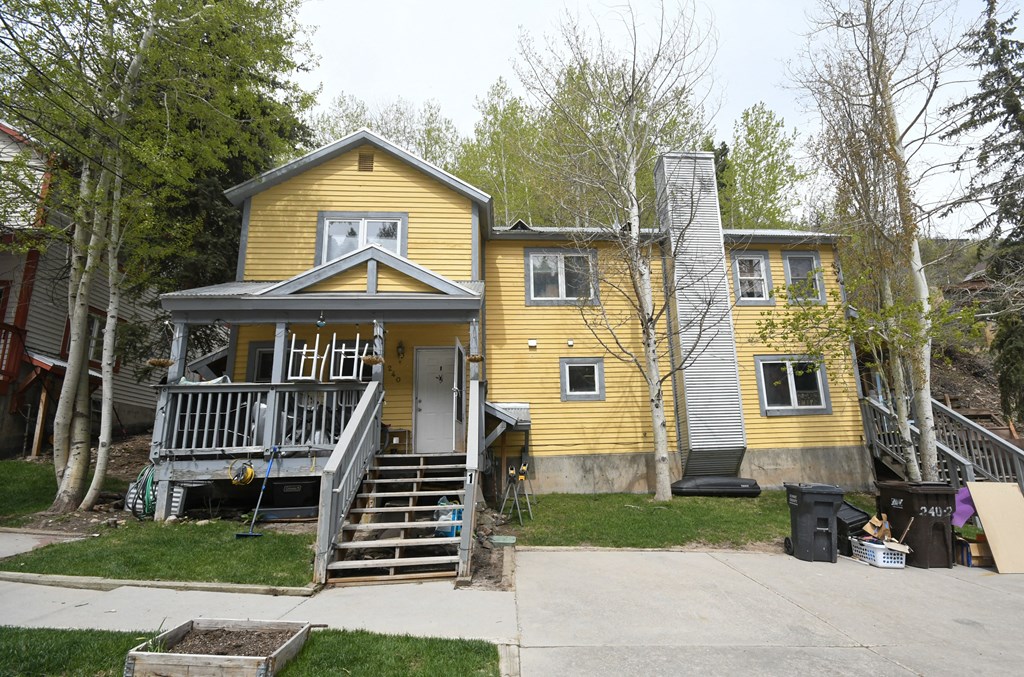 the front of a yellow house with a porch and stairs