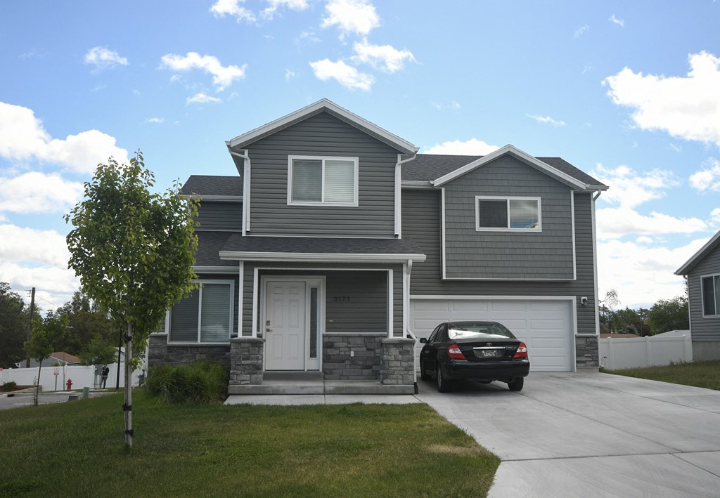 the front of a house with a car parked in the driveway