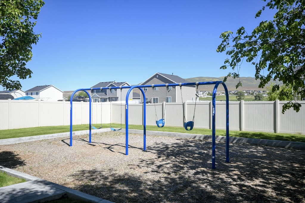 a blue swing set in a park with houses in the background
