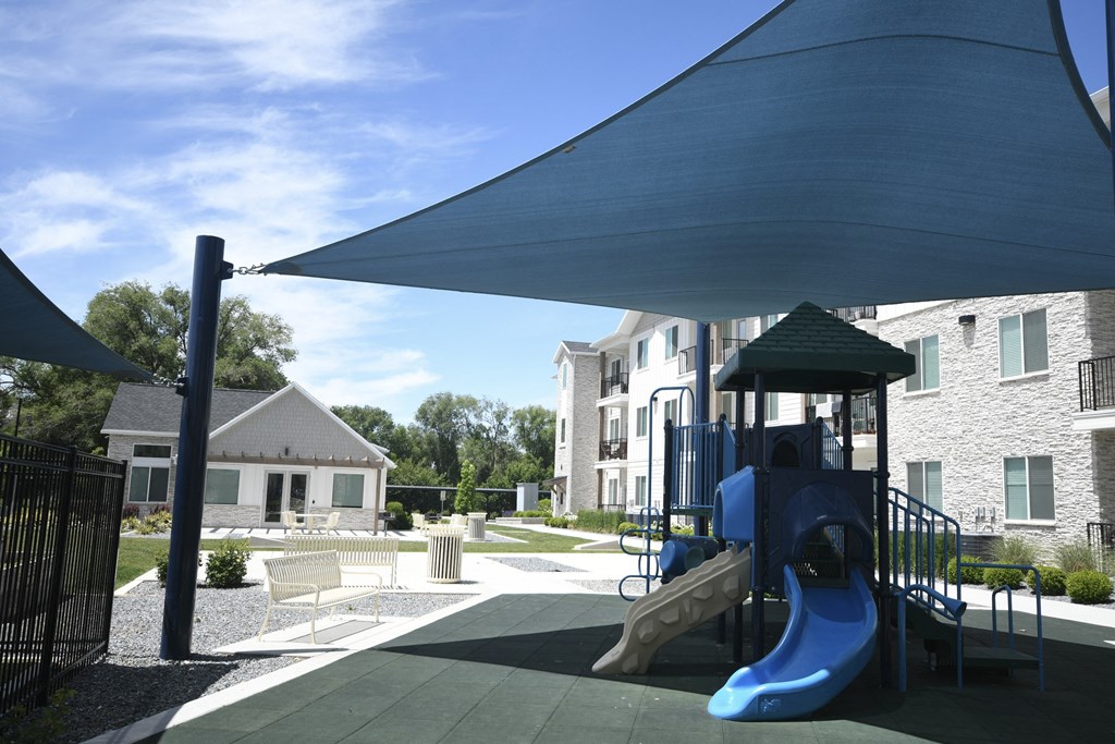 a playground with a blue swing set and a shade canopy