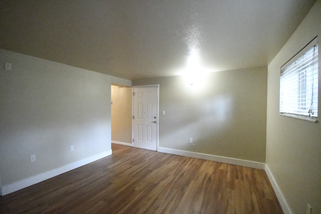 an empty living room with wood floors and white walls