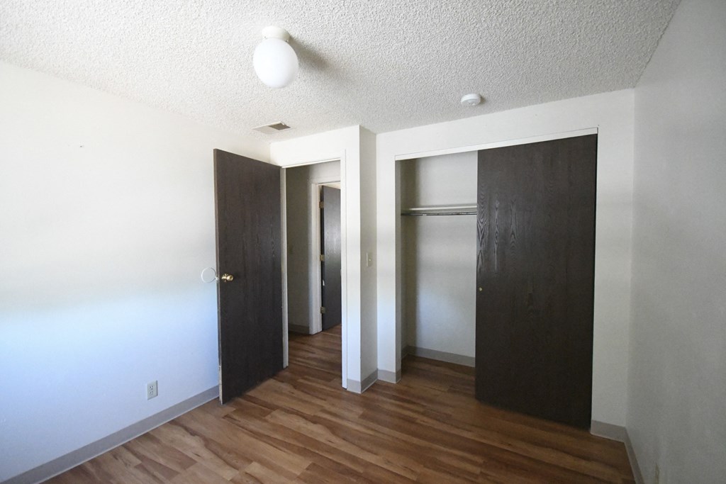 an empty room with three closets and a hard wood floor