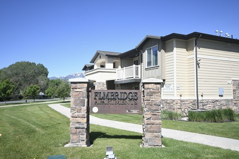 a house with a sign in front of a lawn and a sidewalk