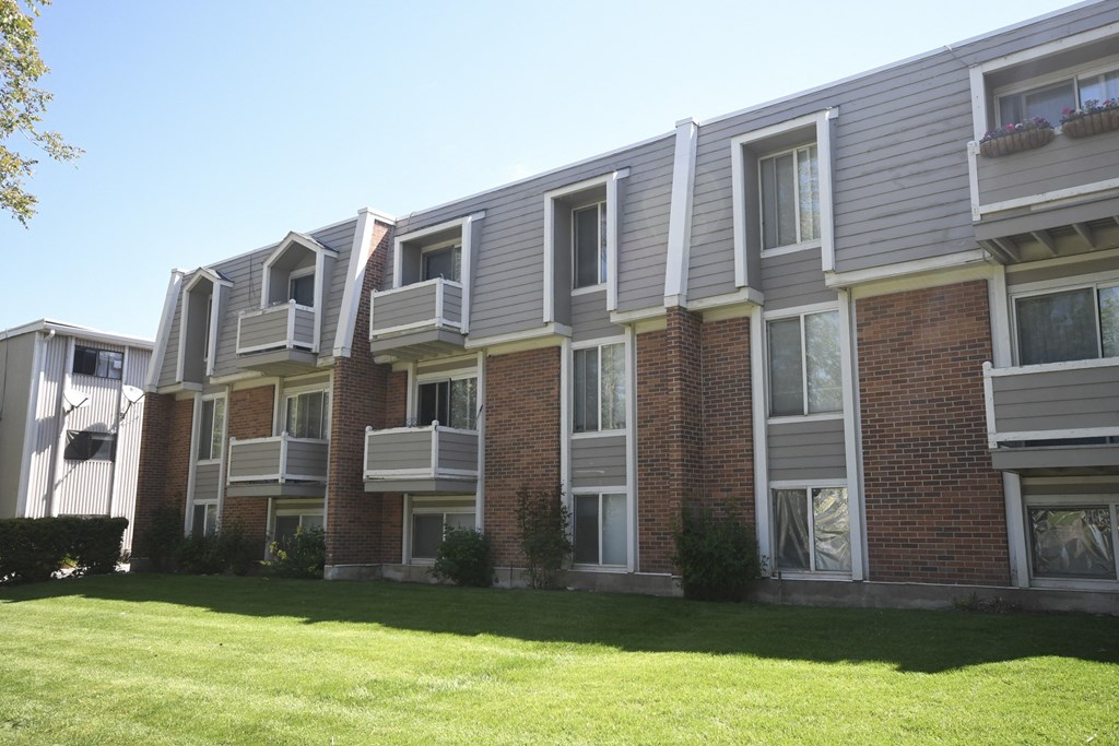 an apartment building with a green lawn in front of it