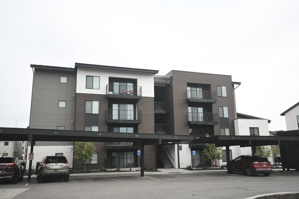 the apartment building has a parking lot with cars in front of it