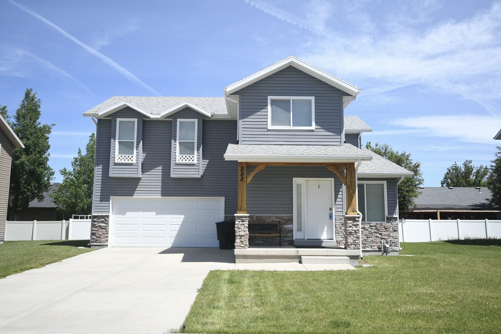 a blue house with a white garage door and a lawn