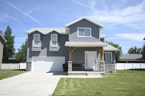 a blue house with a white garage door and a lawn