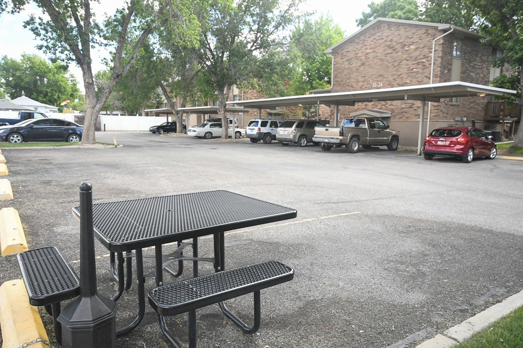 a parking lot with a table and benches in front of a building