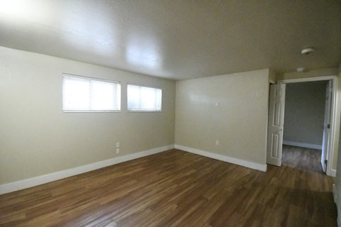 an empty living room with wooden floors and white walls