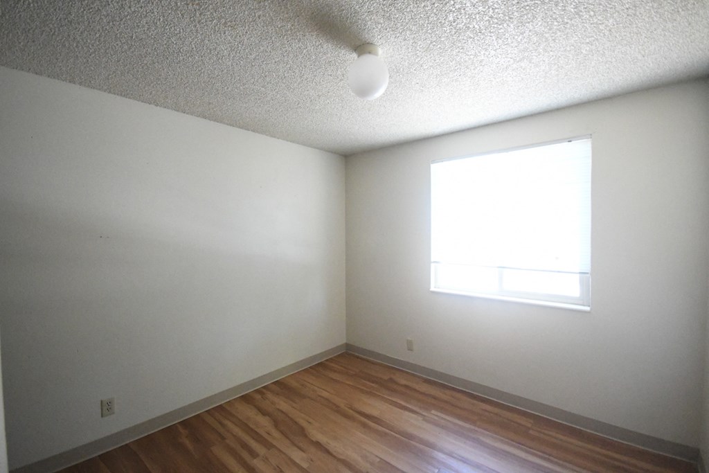 an empty room with wooden floors and a window
