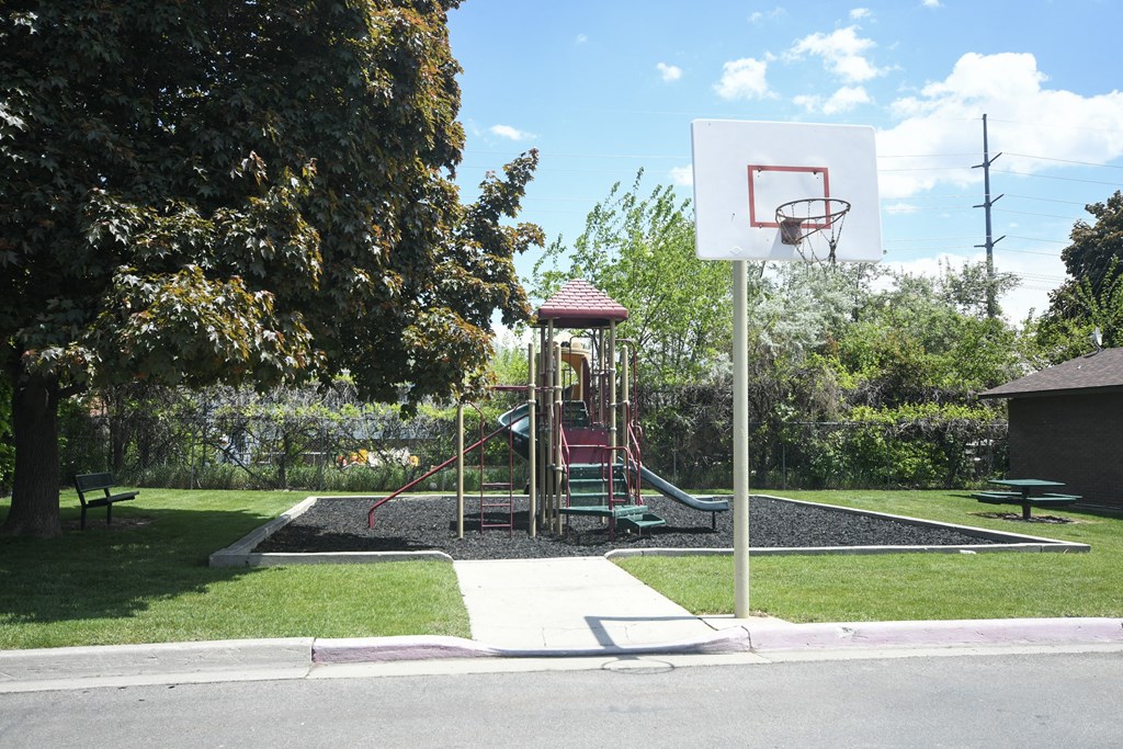 a playground with a basketball hoop and a swing set