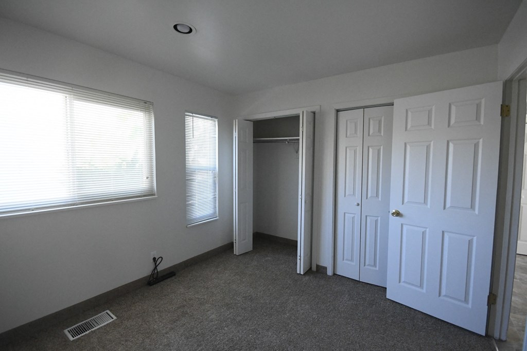 a bedroom with a closet and a window and a door