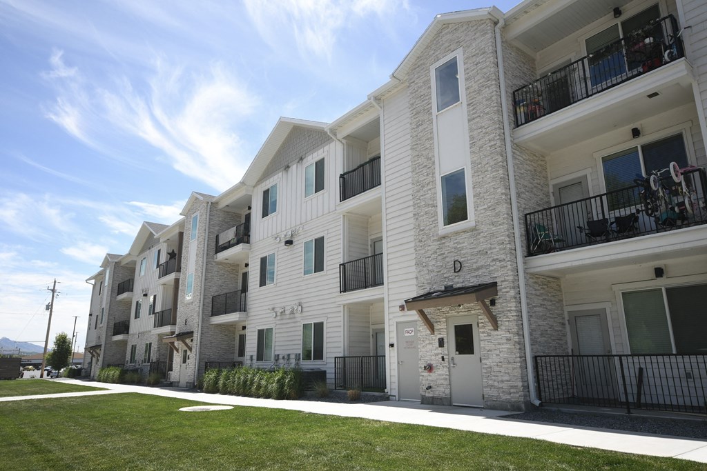a row of white apartment buildings with balconies and a lawn