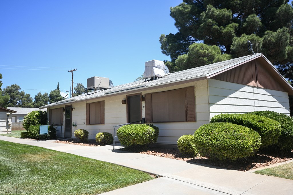 a white house with a brown roof and a sidewalk