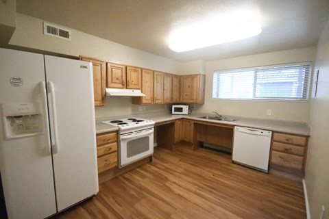 a kitchen with wood flooring and white appliances