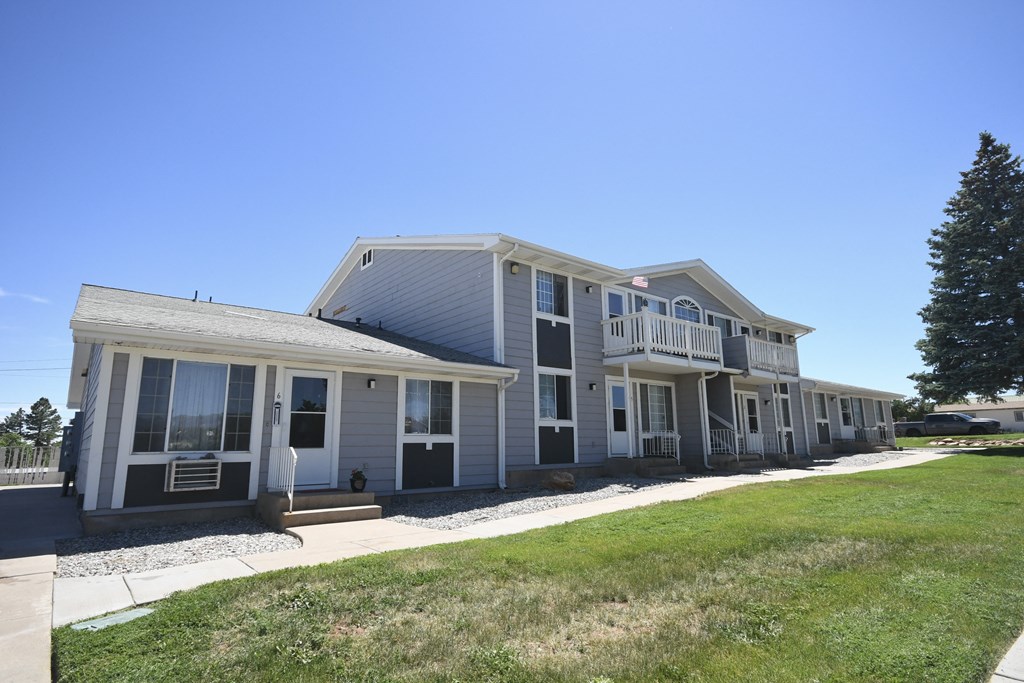 a gray house with a lawn and a blue sky