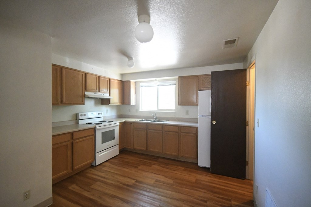 an empty kitchen with wood flooring and wooden cabinets