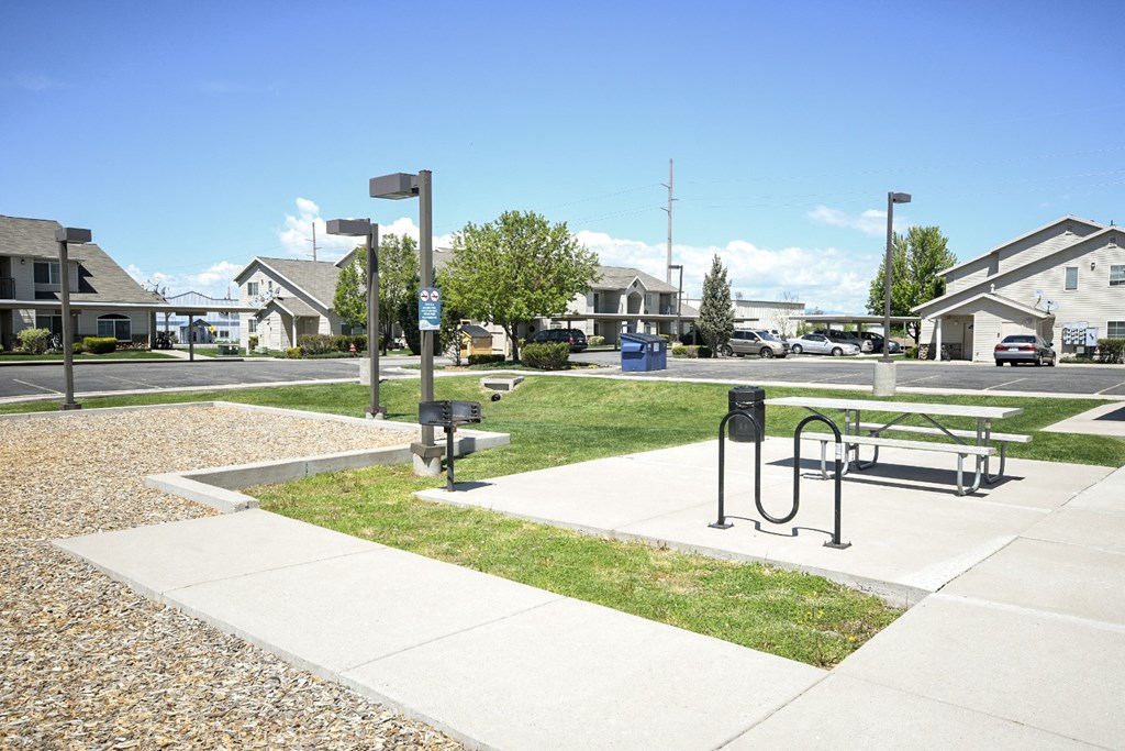 a park with a bench and a picnic table on the sidewalk