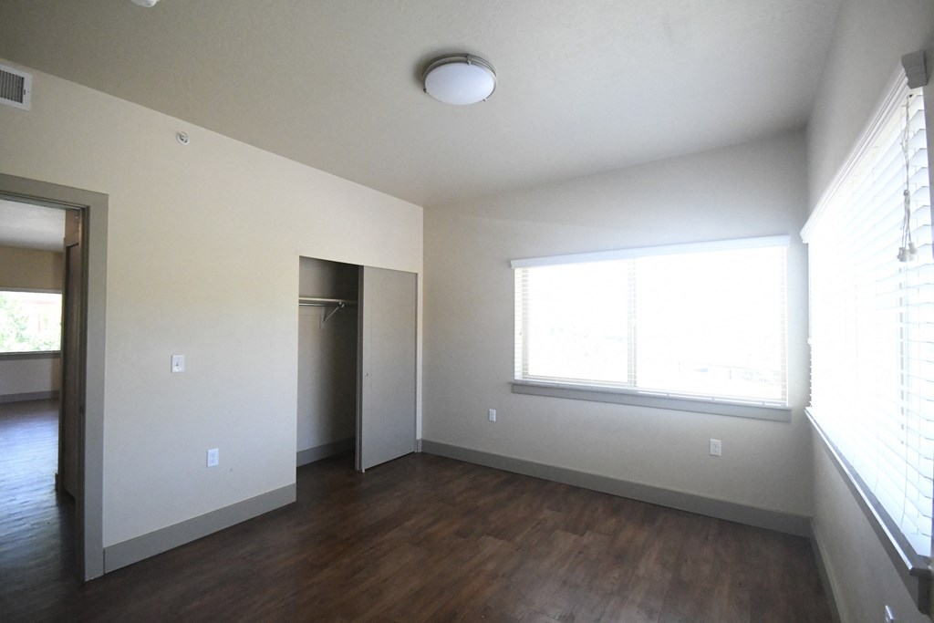 an empty living room with wood floors and a window