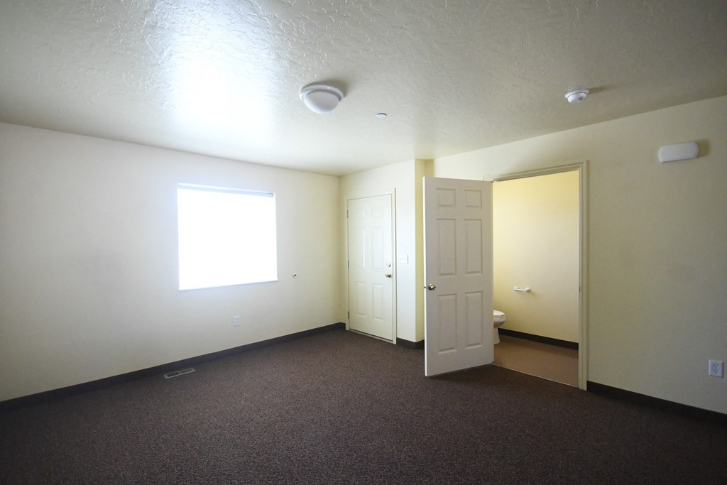 an empty living room with a door and a window