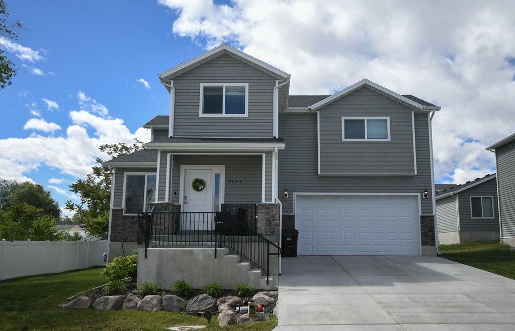 a gray house with a driveway and a garage door