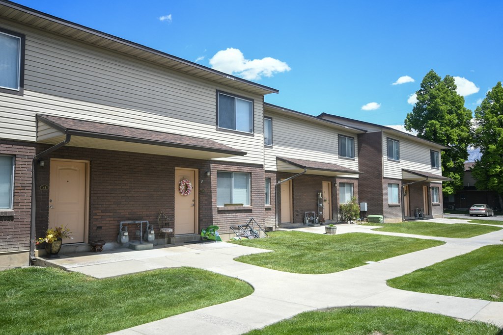 a sidewalk in front of a row of houses with grass