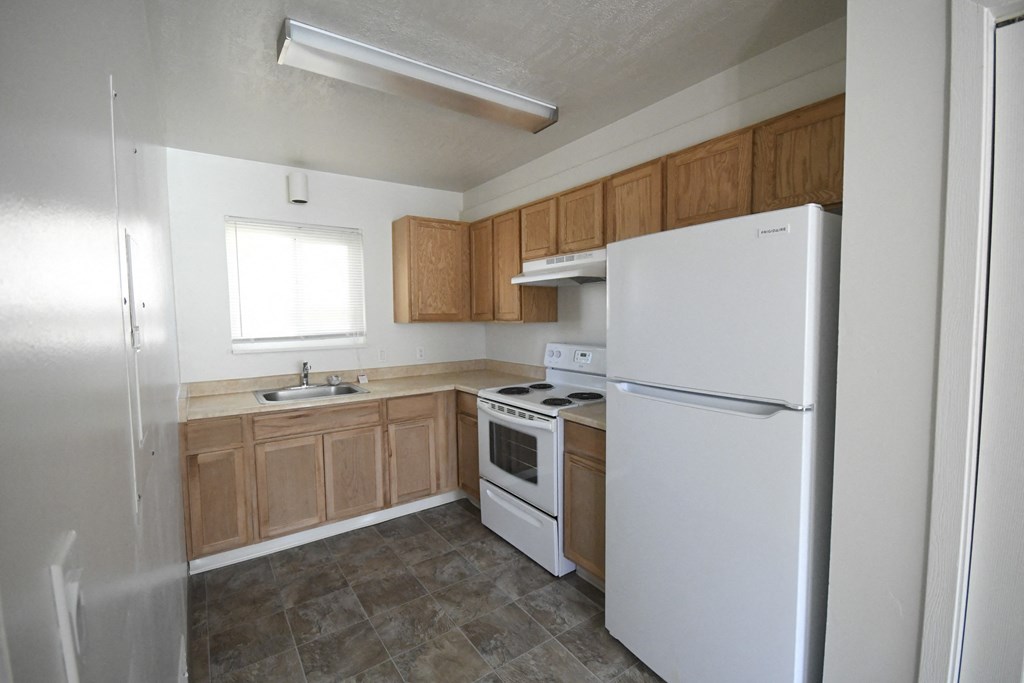 an empty kitchen with white appliances and wooden cabinets