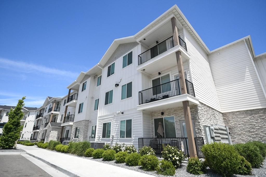 a row of white apartments with balconies and a sidewalk