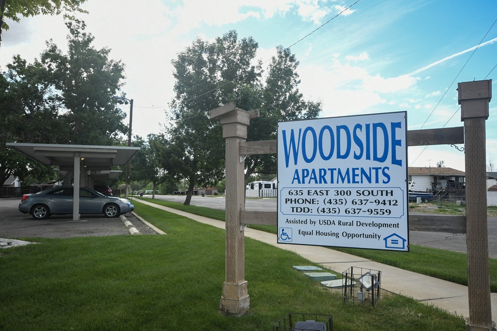 a sign for woodside apartments in front of a parking lot